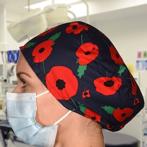Peut inclure: Un bonnet de chirurgien bleu avec un imprimé de coquelicots. Le bonnet est porté par une personne portant une blouse de chirurgien bleue et un masque chirurgical bleu clair.