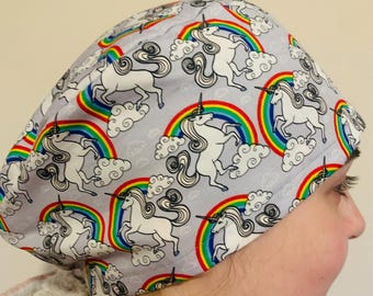 May include: A grey scrub hat with a white unicorn and rainbow pattern. The hat is made of a soft, comfortable fabric and is perfect for healthcare professionals.