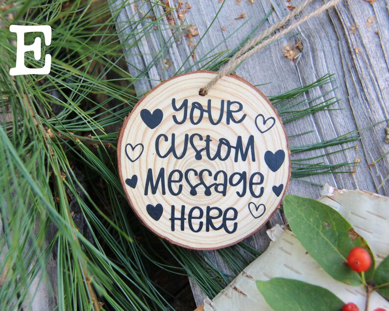 Może przedstawiać: Okrągła drewniana ozdoba z napisem "Your Custom Message Here" i kilkoma czarnymi sercami namalowanymi na niej. Ozdoba jest zawieszona na sznurku jutowym.