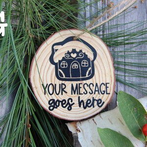 Może przedstawiać: Drewniana ozdoba choinkowa w kształcie piernikowego domku z czarną polewą i sercem na dachu. Ozdoba ma napis "YOUR MESSAGE goes here".