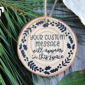 Może przedstawiać: Okrągła drewniana ozdoba z czarno-białym wzorem z liści i jag&oacute;d ostrokrzewu. Ozdoba ma napis "YOUR CUSTOM MESSAGE will appear in this space".