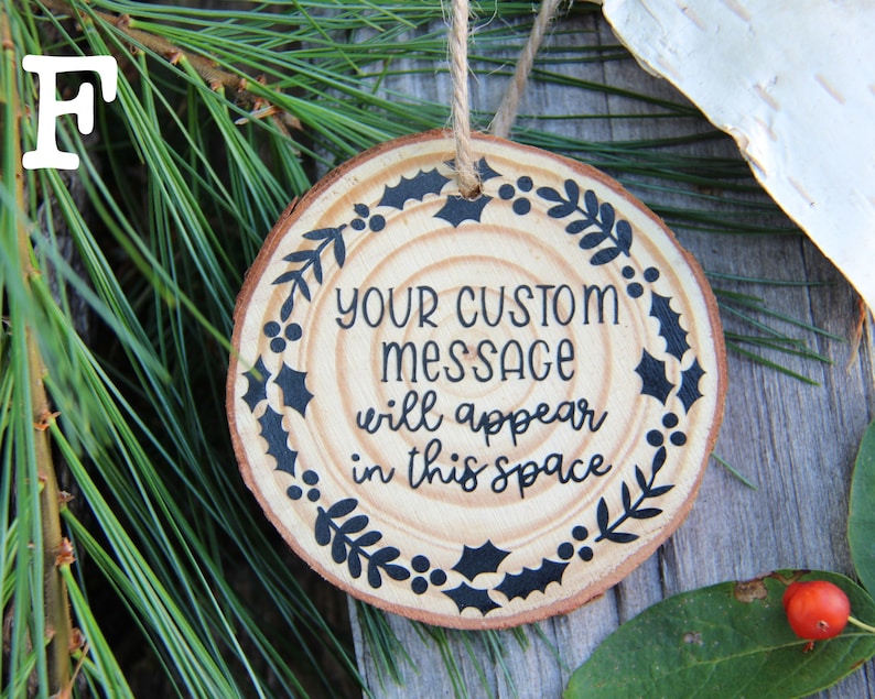 Może przedstawiać: Okrągła drewniana ozdoba z czarno-białym wzorem z liści i jag&oacute;d ostrokrzewu. Ozdoba ma napis "YOUR CUSTOM MESSAGE will appear in this space".