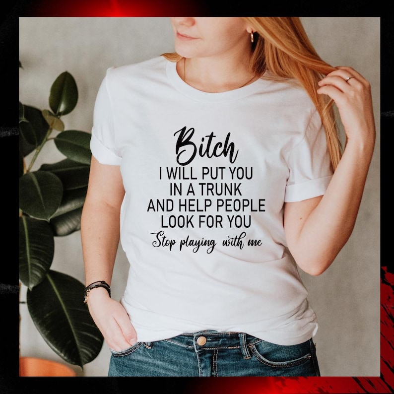 May include: White t-shirt with the text "Bitch I will put you in a trunk and help people look for you. Stop playing with me" in black script. The shirt is worn by a person.