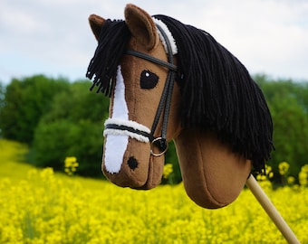 Puede incluir: Una cabeza de caballo marrón y blanca con una crin negra y una brida, de pie en un campo de flores amarillas.