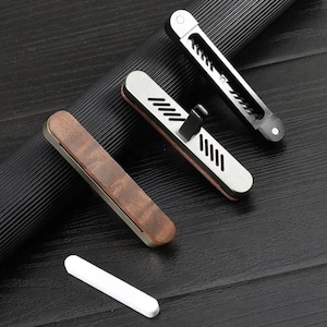 May include: Three car air fresheners, one is wood, one is silver, and one is black. The silver and black air fresheners have a geometric design.