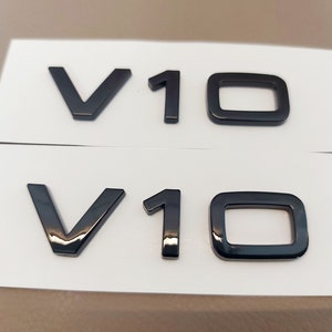 May include: Two black plastic emblems with the text "V10" on a white background.