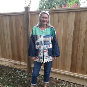 May include: A woman wearing a blue denim jacket with a patchwork quilt lining. The jacket has a white lace trim and the woman is wearing blue jeans and silver shoes.