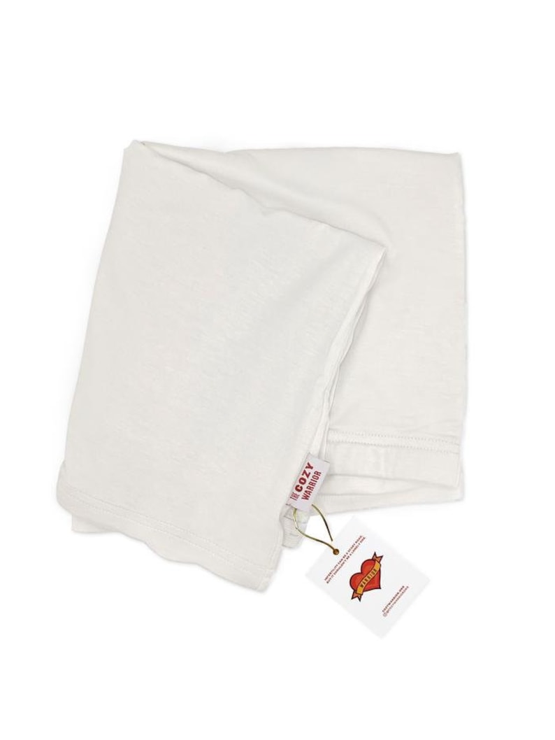 May include: White t-shirt folded with a tag that says "For Cozy Warrior" and a red heart with the word "Warrior" inside.