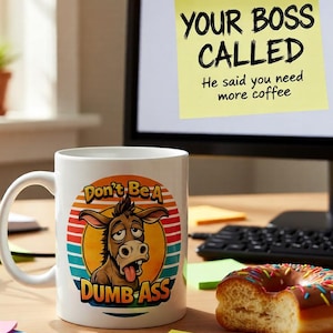 May include: White ceramic mug with a humorous graphic of a donkey and the text "Don't Be A Dumb Ass." A sticky note on a computer monitor reads "Your Boss Called. He said you need more coffee."