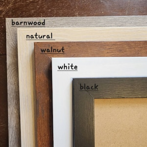 May include: Five picture frames in different colours, from top to bottom: barnwood, natural, walnut, white, and black. The black frame has a corkboard insert.