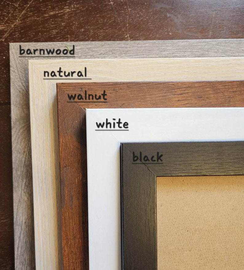May include: Five picture frames in different colours, from top to bottom: barnwood, natural, walnut, white, and black. The black frame has a corkboard insert.