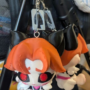 keychains featuring a cartoon character with orange hair, black ears, and red eyes. The character is wearing a white maid outfit with pink accents. The keychains are attached to a silver chain.