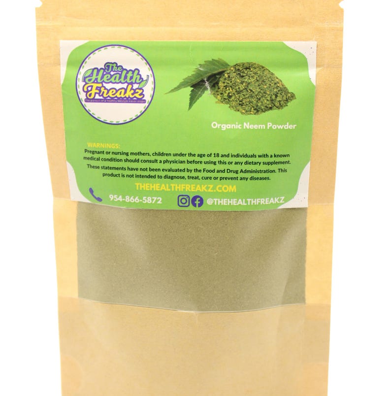 May include: A brown paper bag with a white label that says "The Health Freakz" and "Organic Neem Powder". The label also includes a phone number, website address, and social media handle. The bag contains a green powder.