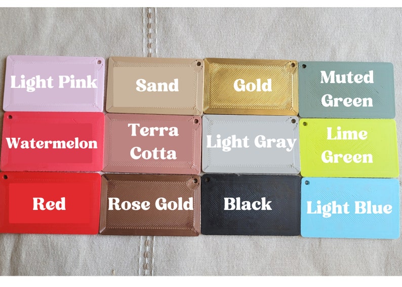May include: A collection of 12 color swatches, each with a different color name printed on it. The colors include light pink, sand, gold, muted green, watermelon, terra cotta, light gray, lime green, red, rose gold, black, and light blue.