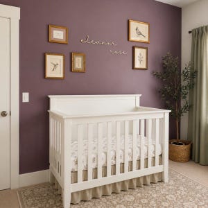 Puede incluir: Una cuna de madera blanca con barrotes verticales, que cuenta con un colchón de estampado floral claro y un faldón de cama beige liso. La pared sobre la cuna está pintada de color morado oscuro y muestra el texto cursivo blanco Eleanor Rose.
