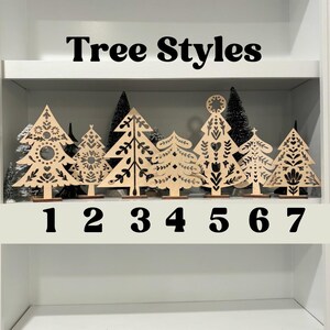May include: Seven different styles of wooden Christmas tree ornaments with black and white designs. The ornaments are numbered 1 through 7. The text "Tree Styles" is at the top of the image.