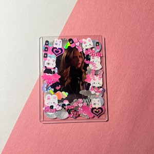 May include: Clear acrylic photo frame decorated with pink, white, and black stickers. The stickers include hearts, bunnies, and other cute designs. The photo inside the frame features a woman with long brown hair.