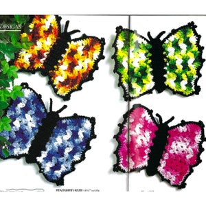 Op de afbeelding: Vier gehaakte vlinderwanddecoraties in verschillende kleuren: blauw en wit, groen en wit, roze en wit, en oranje, geel en wit. De vlinders zijn ongeveer 8 1/2 inch breed. FINISHED SIZE: 8 1/2" wide