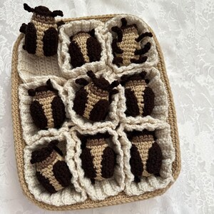 May include: A crocheted beige and brown basket with nine crocheted brown and beige bugs inside.