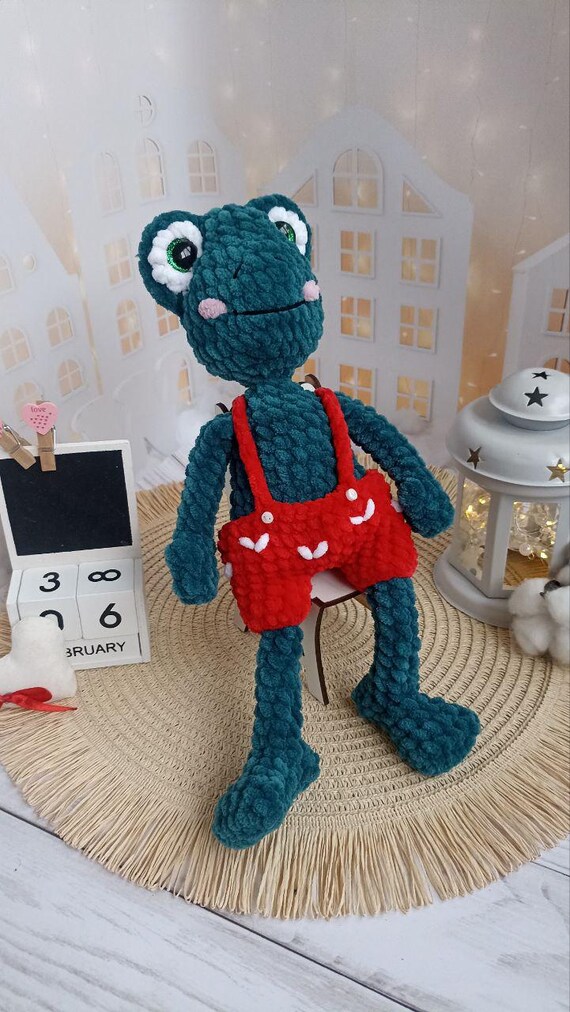 カエルのぬいぐるみ 赤いズボン 赤いパンツをはいたかぎ針編みの緑のカエルのぬいぐるみ。子供やカエル