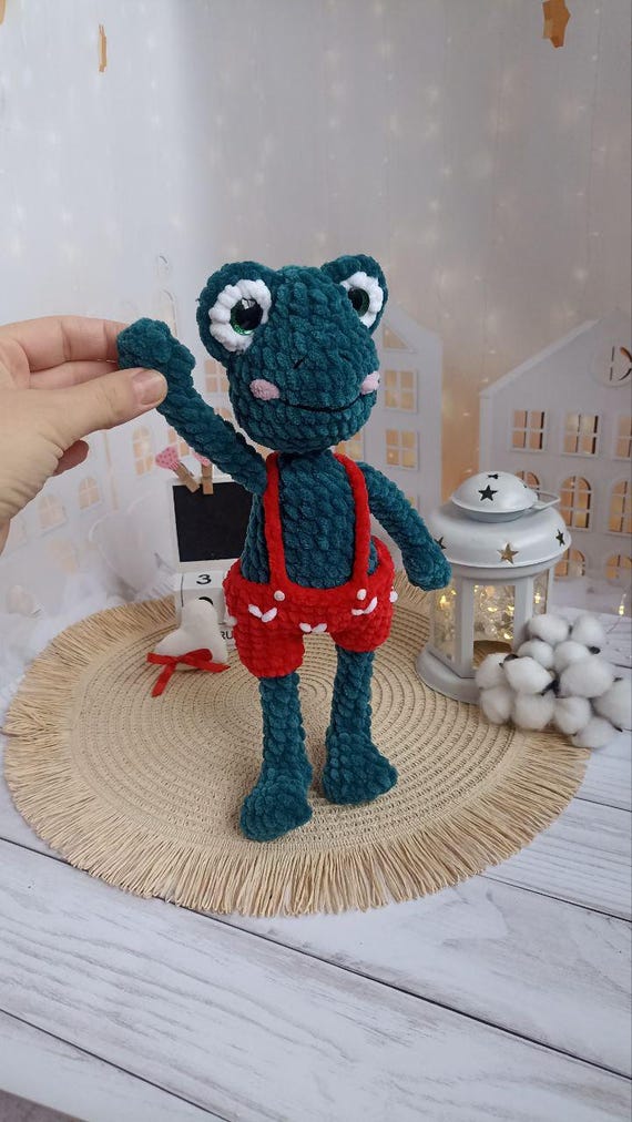 カエルのぬいぐるみ 赤いズボン 赤いパンツをはいたかぎ針編みの緑のカエルのぬいぐるみ。子供やカエル
