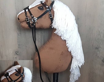 Può includere: Un cavallo a dondolo a forma di testa di cavallo marrone e bianco con una briglia e redini in pelle nera. Il cavallo ha una criniera e una coda bianche.