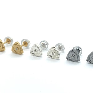 May include: Six pairs of earrings featuring a triangle-shaped design with a small diamond-shaped stone in the center. The earrings are available in gold, silver, and black.