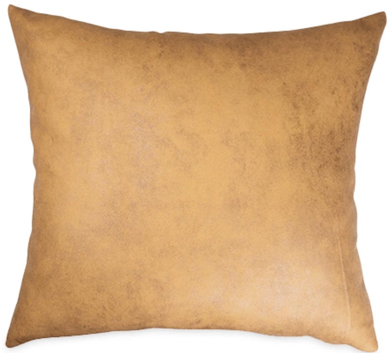 May include: A square, tan-colored pillow with a textured, distressed appearance. The pillow has a solid color and a soft, inviting look. The pillow is likely for home decor, adding a touch of warmth and style to any living space.