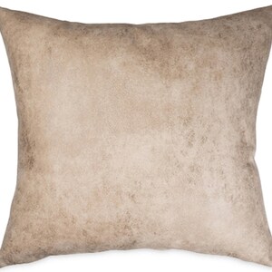 May include: Square decorative pillow with a neutral color palette. The pillow features a textured, mottled design in shades of beige and brown, creating a rustic or vintage aesthetic. The pillow is likely used for home decor.