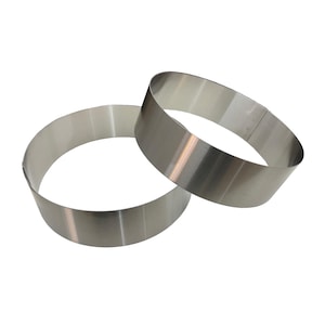 May include: Two stainless steel cake rings, each with a circular shape. The rings are made of a shiny, silver-coloured metal. They are designed for baking and are likely used to shape cakes or other desserts. The rings are approximately 10 cm in diameter.