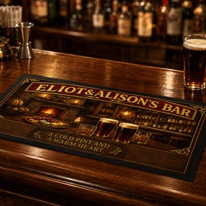 May include: A rectangular bar mat featuring a dark wood background with a fireplace, a platter of food, and glasses of beer. The text reads ELIOT & ALISON'S BAR and A COLD PINT AND A WARM HEART. The design includes gold filigree accents on the corners.