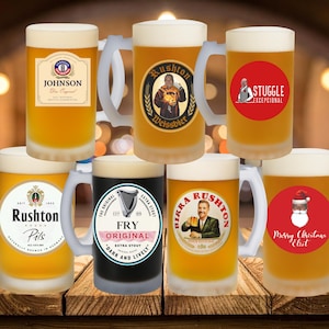 May include: A collection of frosted beer tankards filled with beer, each with a different label. Labels include "Johnson", "Rushton Weissbier", "Stuggle Excepcional", "Rushton Pils", "Fry Original Extra Stout", "Birkka Rushton", and a Christmas-themed mug.