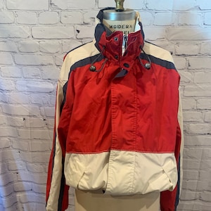 May include: Red, white, and navy blue windbreaker jacket with a zipper closure and a hood. The jacket has a white stripe down each sleeve and the text "MODERN MODEL" on the back of the hood.