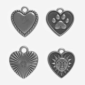 May include: Four silver-toned heart-shaped charms. One has a rope-like border, another a paw print, a third has a sunburst design, and the last features a sun face. Each charm has a small loop at the top for attachment.