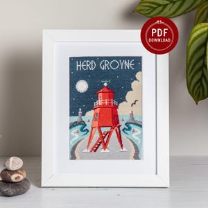 May include: A cross-stitch pattern in a white frame featuring a red lighthouse on stilts against a dark blue night sky with a moon. The text HERD GROYNE is stitched at the top. The scene includes light blue water, a sandy path, and a red PDF download seal.