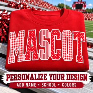 May include: A red crewneck sweatshirt featuring the word MASCOT in large block letters. Each letter has a white outline and a distinct pattern: red and white gingham, white polka dots on red, or vertical white stripes on a red background.