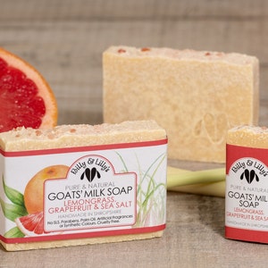 May include: Two bars of goat's milk soap with lemongrass, grapefruit and sea salt. The soap is handmade in Shropshire, England. The soap is wrapped in white paper with red and green text. The soap is sitting on a wooden surface with a grapefruit and pink Himalayan salt.