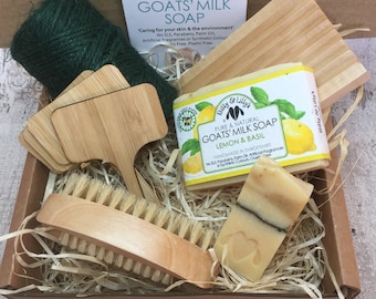 May include: A gift box filled with natural goat milk soap, a wooden brush, and wooden plant markers. The soap is labelled "Pure & Natural Goats' Milk Soap Lemon & Basil" and is handmade in Shropshire. The box is filled with shredded paper.