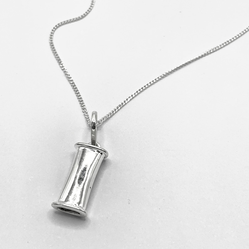 Sterling silver breathing necklace pendant on a bright neutral background.