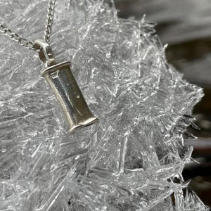 Sterling silver breathing necklace resting on clear ice.