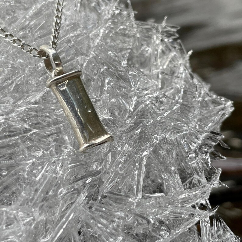 Sterling silver breathing necklace resting on clear ice.
