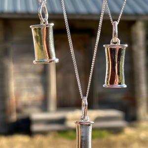 Three sizes of sterling silver breathing pendants hanging together.