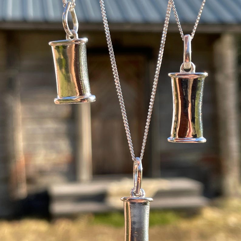Three sizes of sterling silver breathing pendants hanging together.