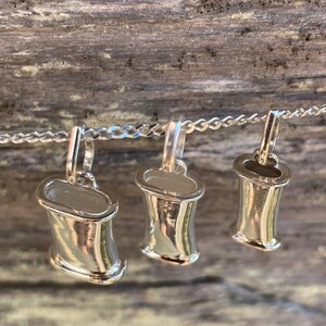 Three sterling silver breathing necklace sizes arranged on natural wood.