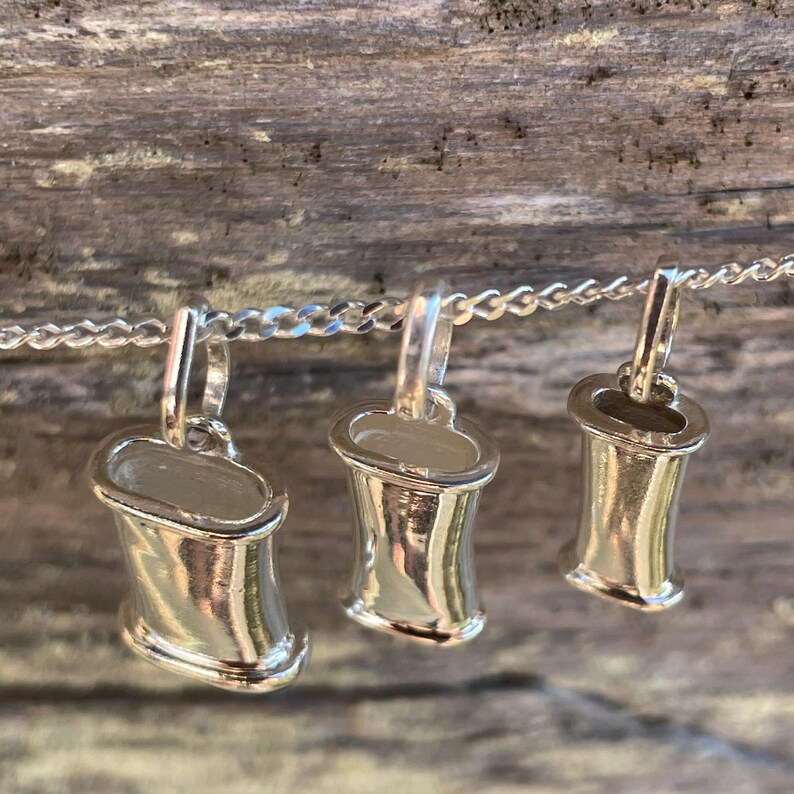 Three sterling silver breathing necklace sizes arranged on natural wood.