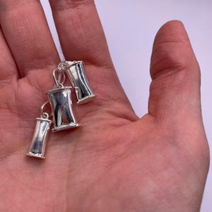 Three sizes of sterling silver breathing pendants held together in one hand.