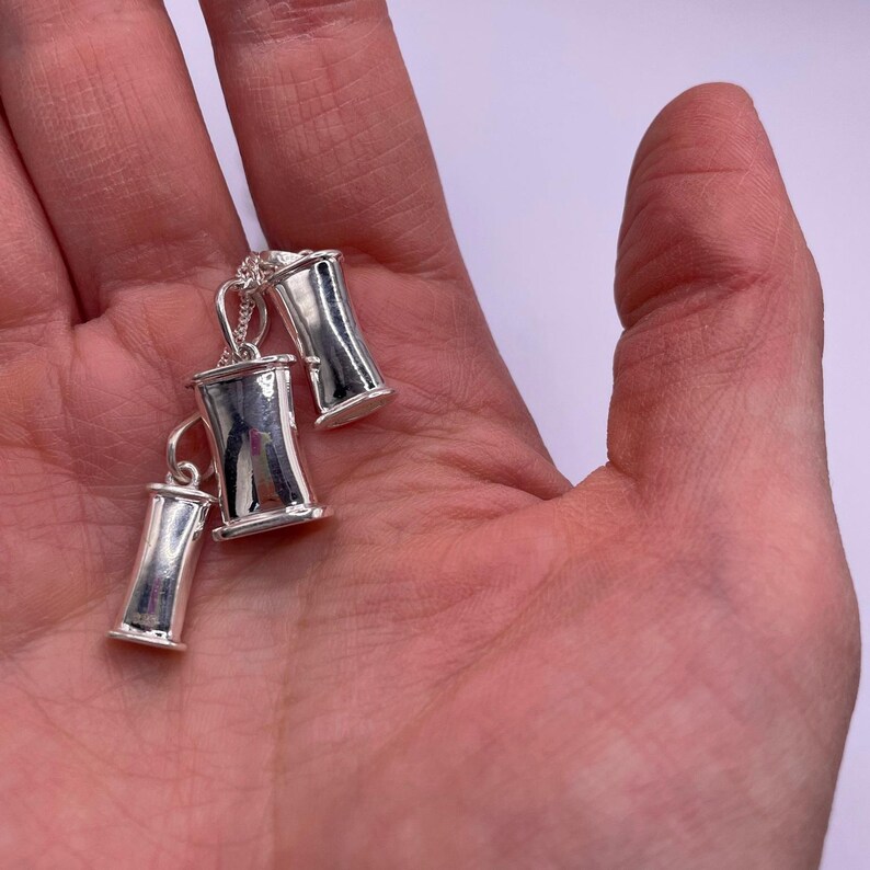 Three sizes of sterling silver breathing pendants held together in one hand.