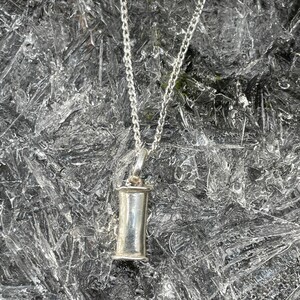 Sterling silver breathing pendant hanging above a winter ice background.