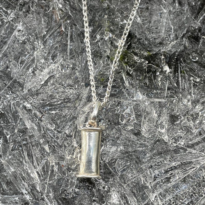 Sterling silver breathing pendant hanging above a winter ice background.