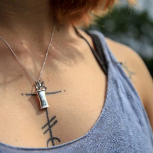 Person wearing a sterling silver breathing necklace to show its scale on the body.